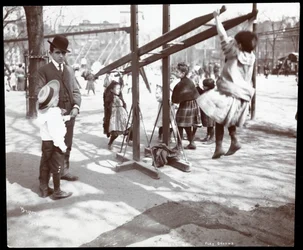 Vy över en man som övervakar barn som leker på lekredskap i Tompkins Square Park, på Arbor Day, New York, 1904 (silvergelatintryck)
